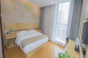 Una habitación de hotel con cama, mesita de noche, lámpara y cortinas.