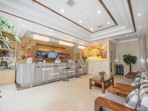 A hotel reception area with a reception desk, seating area, and a large autumn-themed wall mural.