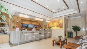 Een hotel receptie met een receptiebalie, een zithoek en een grote muurschildering met herfstthema.