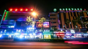 Een helder verlicht bedrijfsgebouw met neonreclame, waaronder een hotel genaamd "GroomTree Inn Express" en een bedrijfsencentrum.