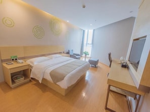 A modern hotel room with a large bed, bedside tables, a desk, and a television.