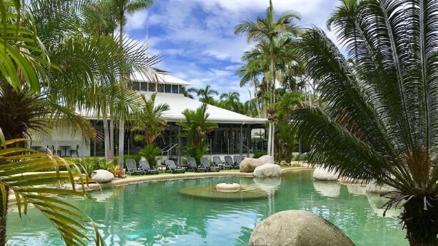 A pool area with lounge chairs and palm trees.