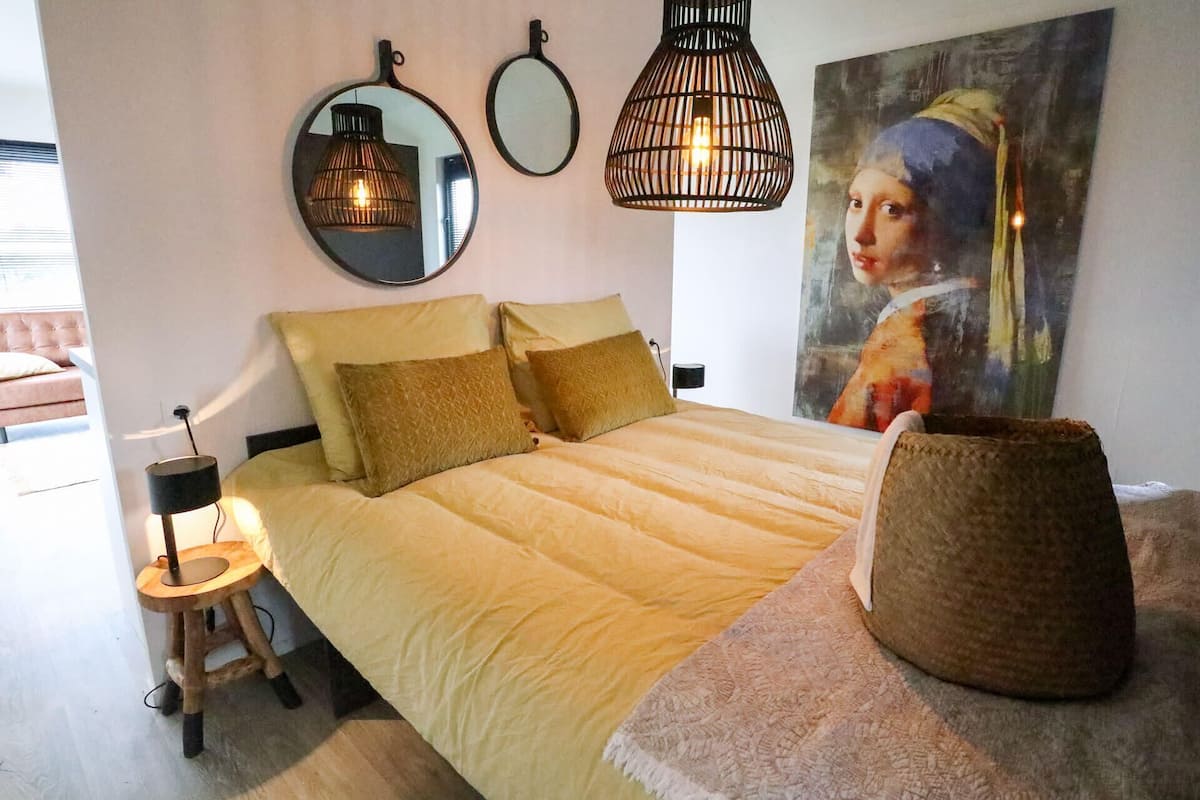 Une chambre à coucher avec un lit, des lampes de chevet, un miroir et un tableau accroché au mur.