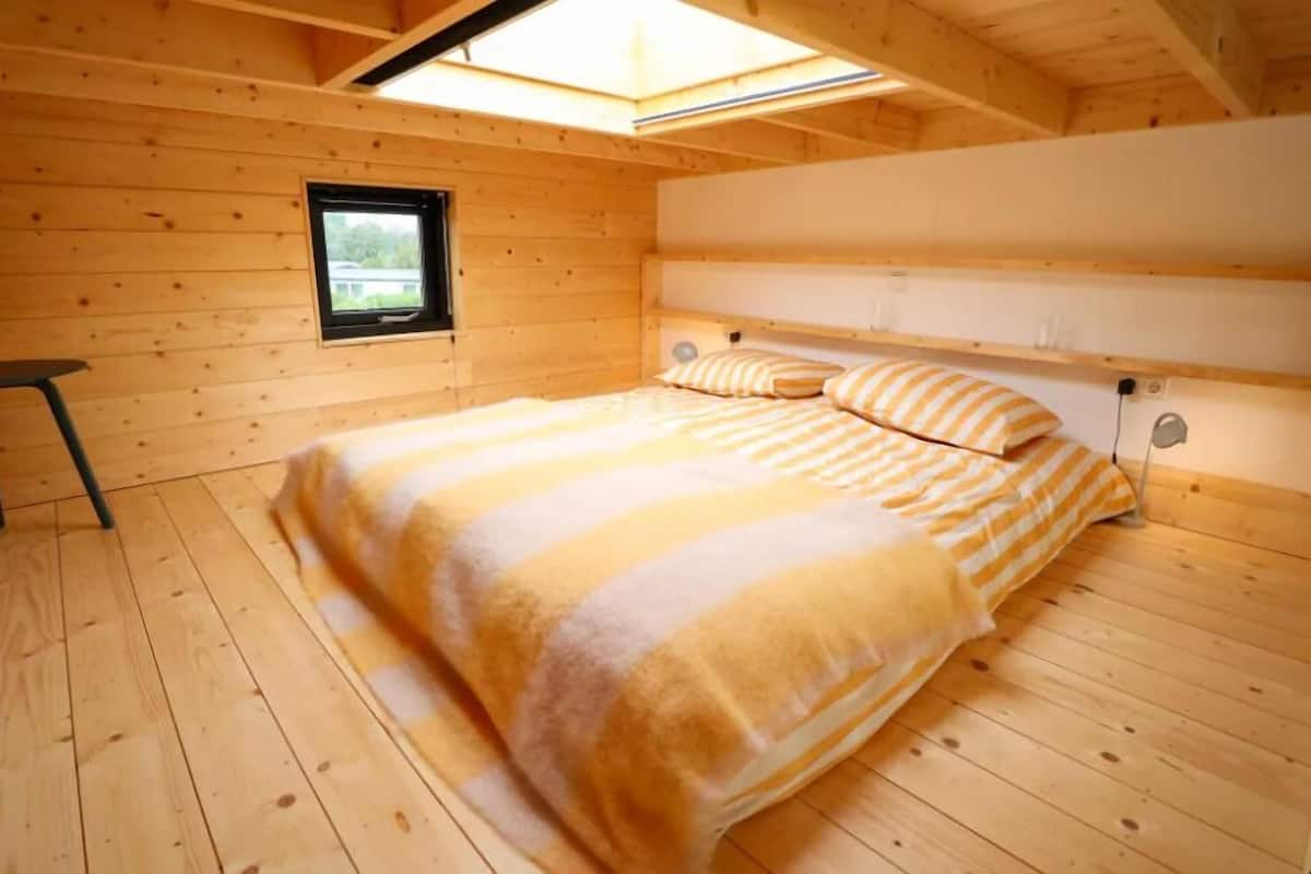 Une chambre dans une cabane en bois, avec un lit, une fenêtre et une lucarne.