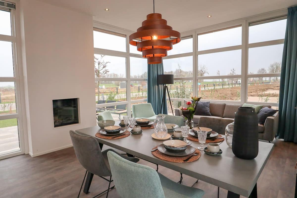 Un coin repas avec une table dressée pour quatre personnes, de grandes fenêtres et une vue sur l’extérieur.
