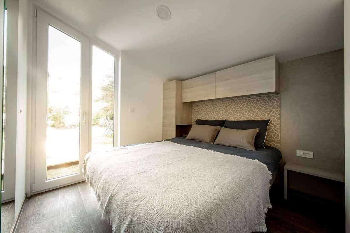 Une chambre dotée d’un grand lit, d’une porte-fenêtre coulissante et de meubles encastrés.