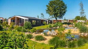 A modern residential area with houses, a small pond, and well-maintained gardens. - Europarcs Marina Strandbad (Olburgen)