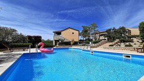 Ein Swimmingpool mit einem rosa Flamingo-Schwimmpunkt, umgeben von Steinstufen und einem Gebäude mit einem geneigten Dach.
