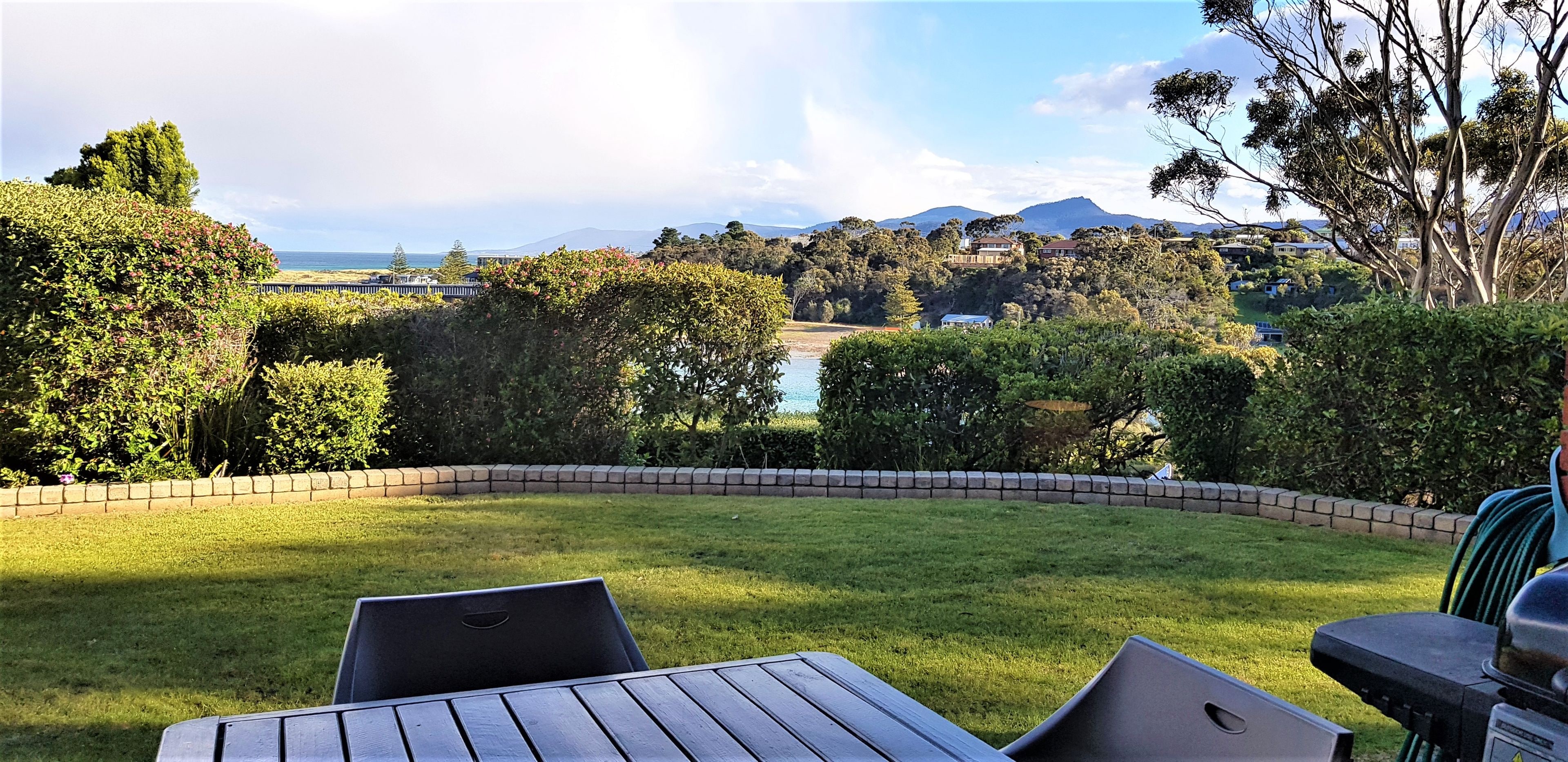 A grassy outdoor area with a view of a body of water and distant hills.
