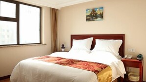Habitación de hotel con una cama grande, una mesita de noche, un teléfono y una ventana con cortinas.