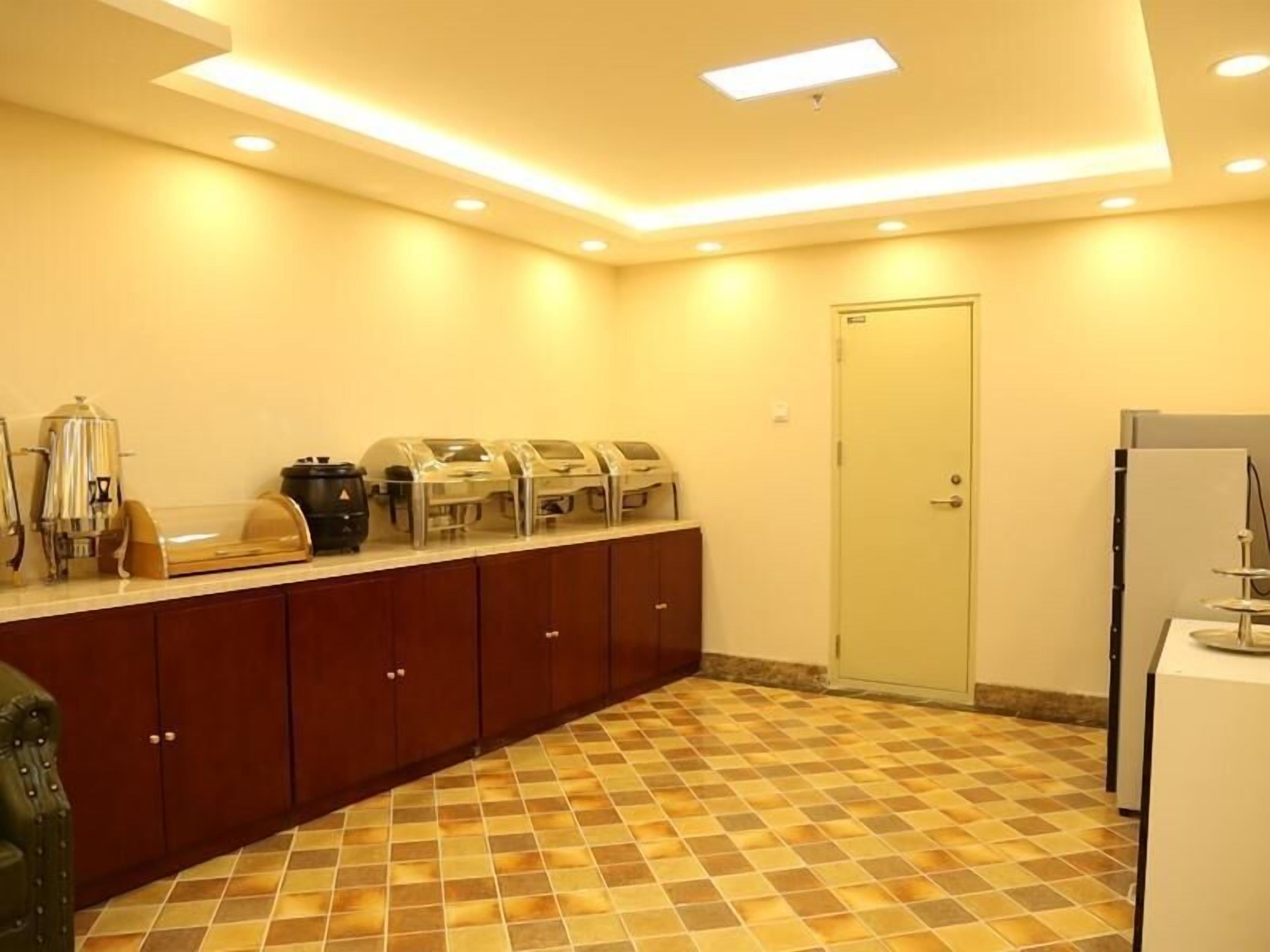 Una cocina de hotel con una barra de desayuno buffet, un refrigerador y una puerta.