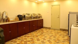 Una cocina de hotel con una barra de desayuno buffet, un refrigerador y una puerta.
