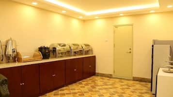Una cocina de hotel con una barra de desayuno buffet, un refrigerador y una puerta.