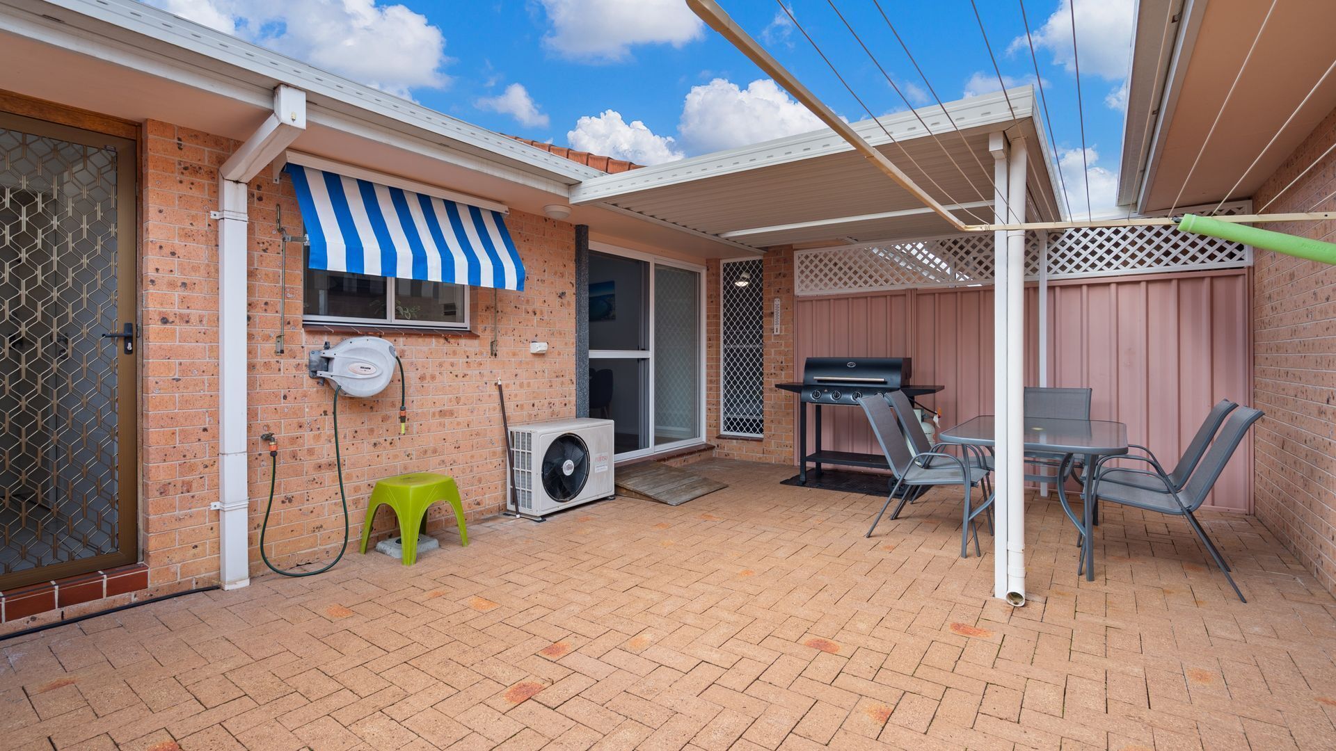 Een achtertuin met een barbecue, zitplaatsen buiten en een overdekte patio.