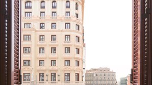Vista desde un balcón con barandilla, con vistas a un edificio de varios pisos de arquitectura clásica, que incluye una torre y numerosas ventanas.