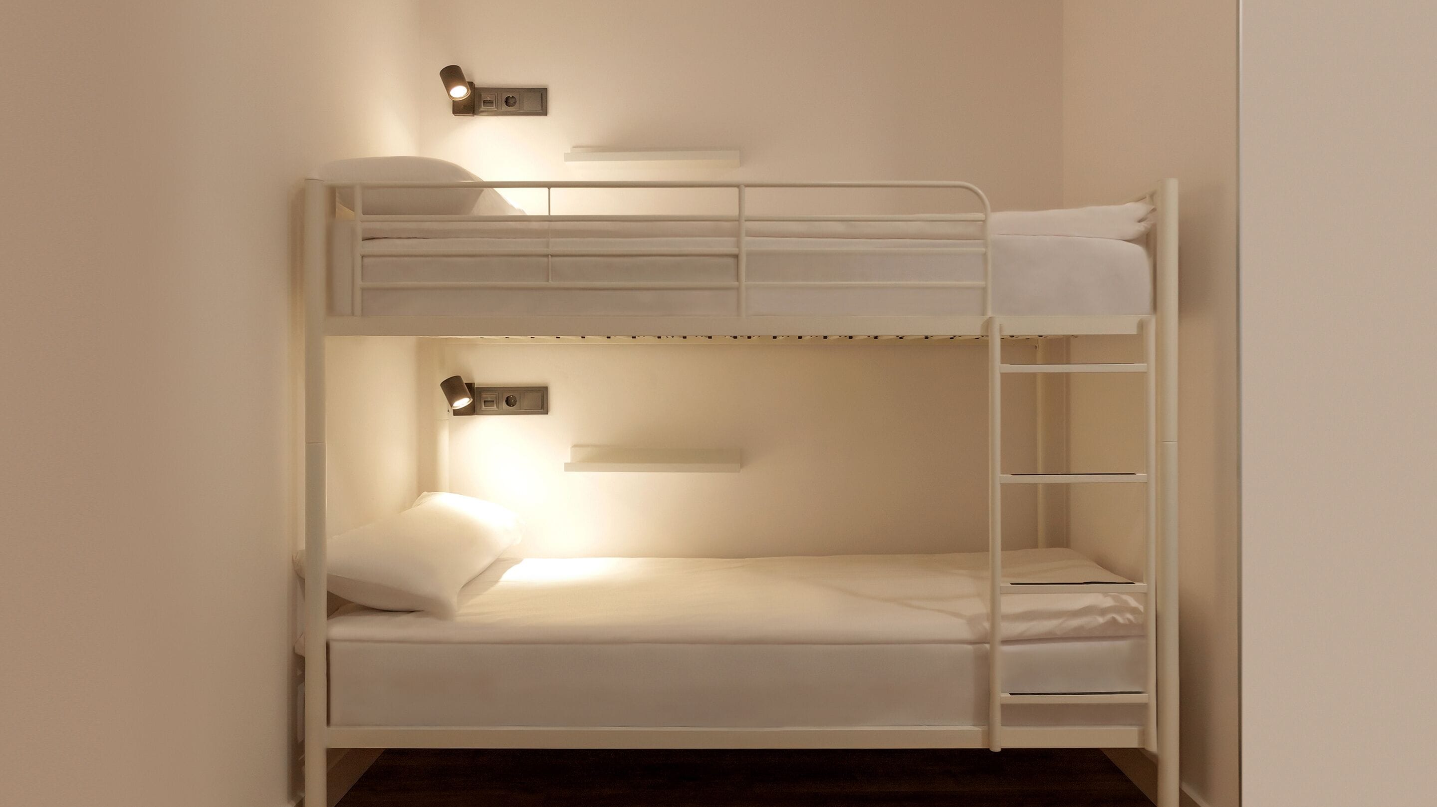 A bunk bed with a bedside table and a wall-mounted light fixture.