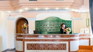 A reception desk with a green headboard, a vase with flowers, and a sign on the wall.