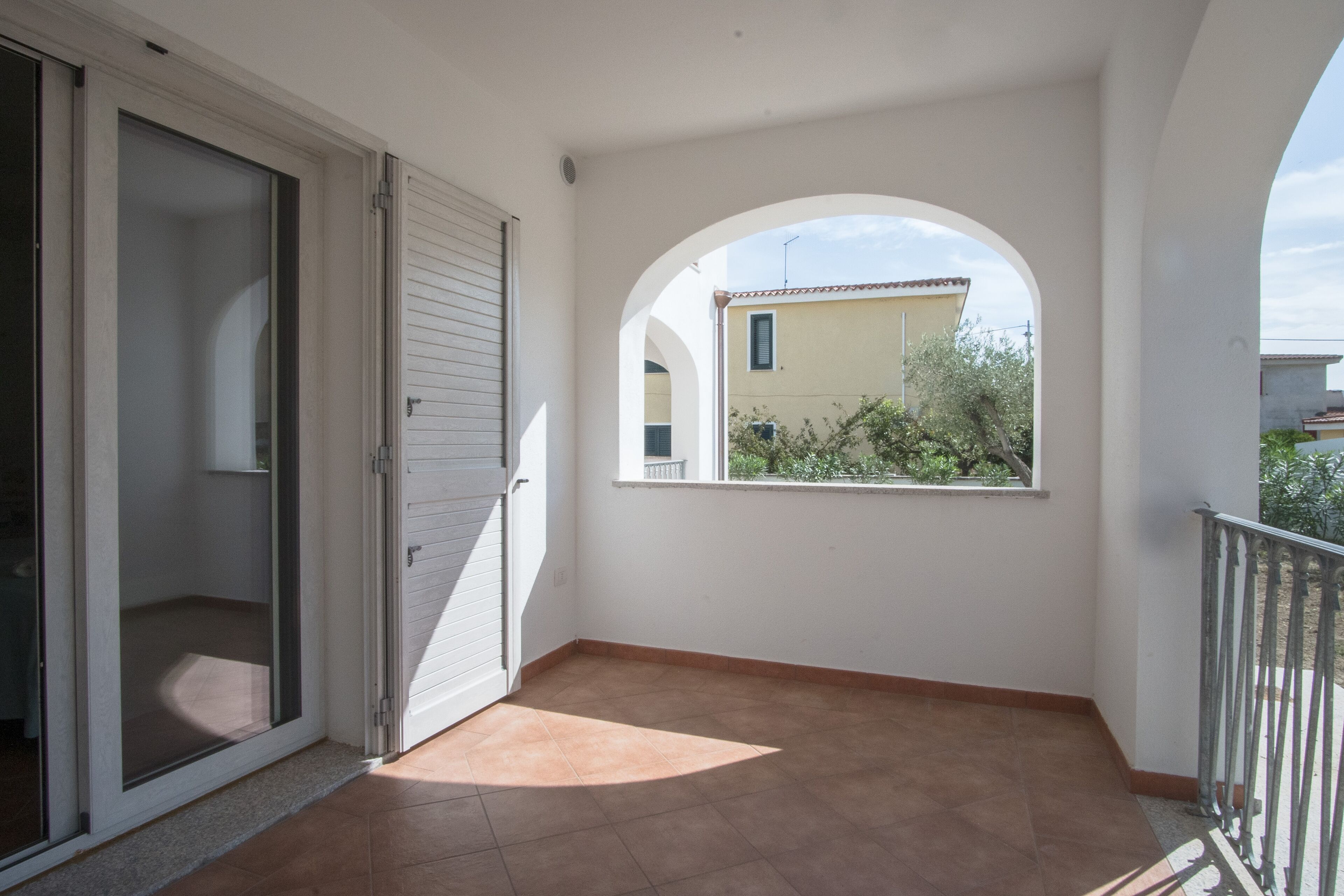 A balcony with a view of a building and vegetation.