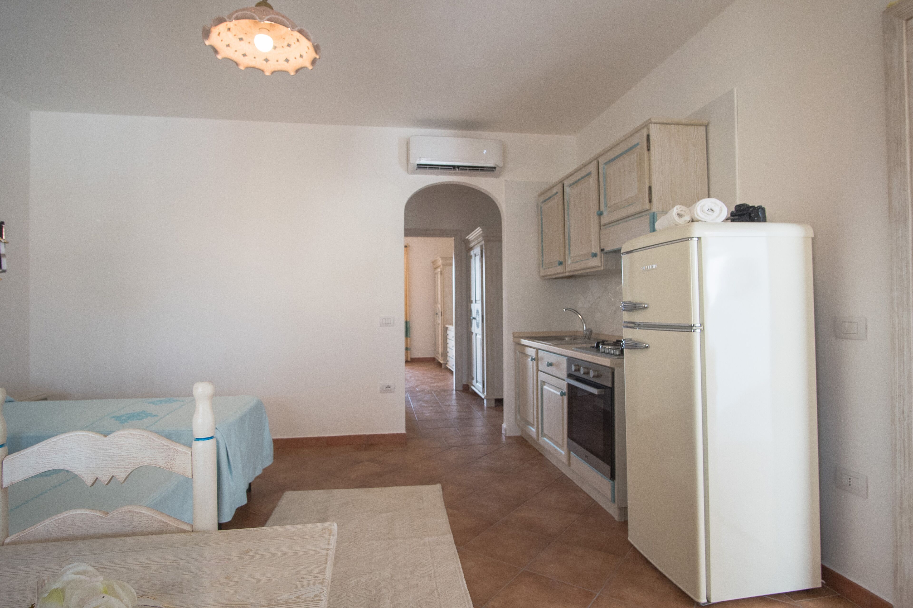 A compact kitchen with a refrigerator, oven, and sink. There is a dining area with a table and chairs.