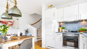 Eine moderne Küche mit weißen Schränken, einem eingebauten Backofen und einem Holztisch mit Blumen in einer Vase.