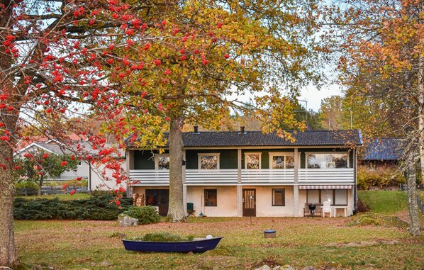 A two-story house with a front porch, a small boat in the yard, and a tree with red berries. - Lovely home in Tranås with sauna (Tranås)
