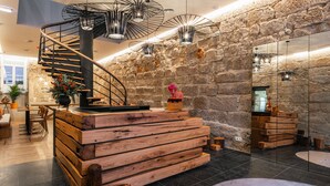 A modern interior with a spiral staircase, wooden furniture, stone walls, and contemporary lighting fixtures. - Porto River Infante (Porto)