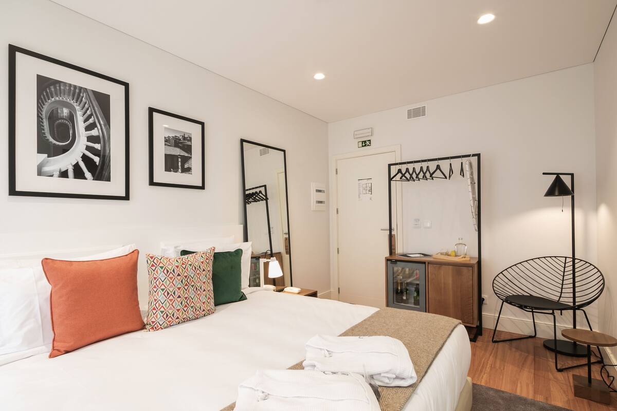 Una habitación de hotel con cama, espejo, armario, silla y escritorio.