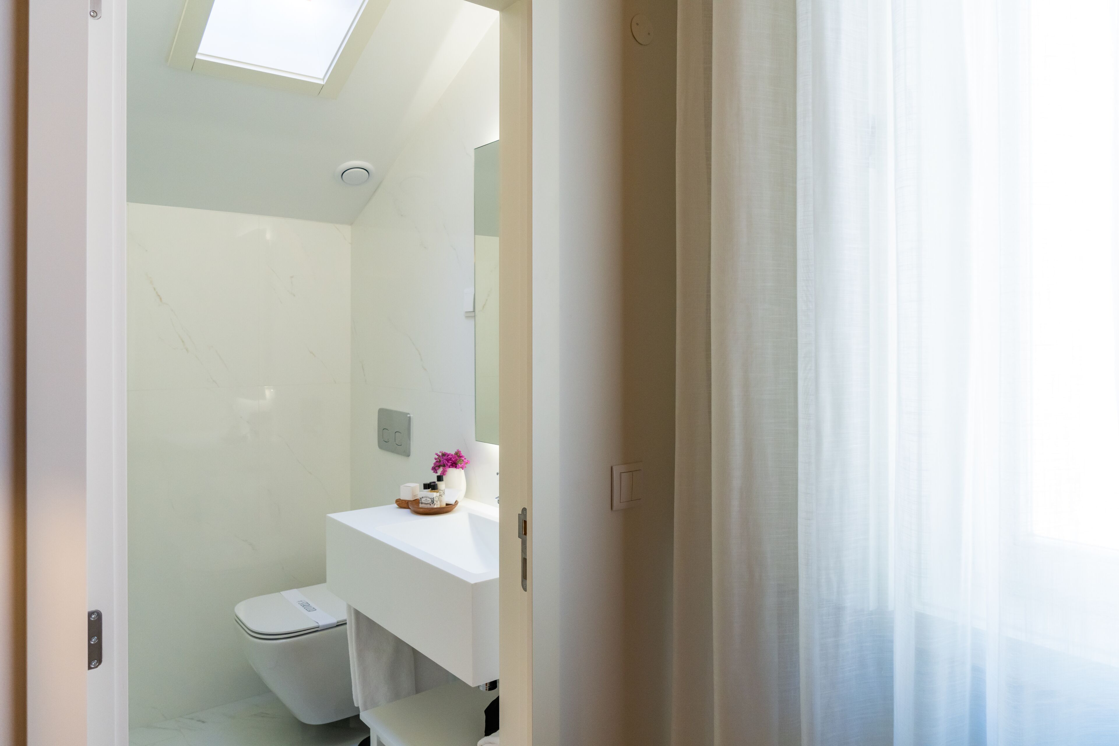A modern bathroom with a toilet, a sink, and a mirror.