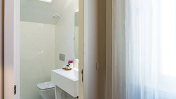 A modern bathroom with a toilet, a sink, and a mirror.