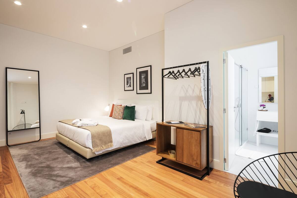 Un dormitorio moderno con cama, mesita de noche y espejo.