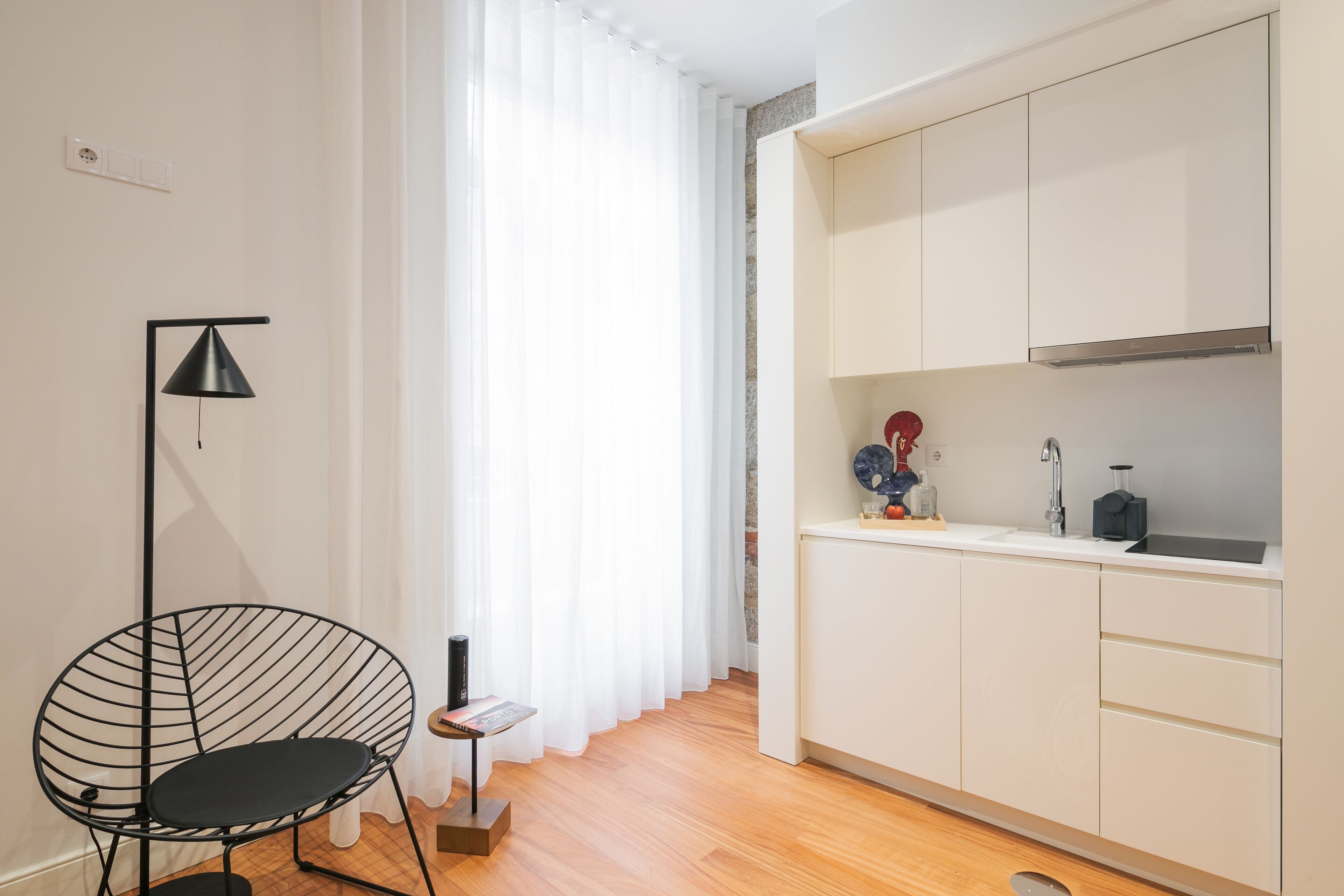 A modern kitchen with white cabinets, a black floor lamp, and a small side table.