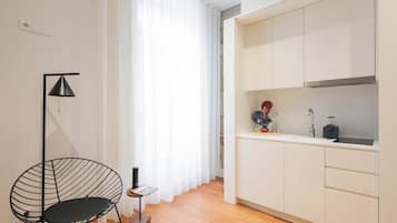 A modern kitchen with white cabinets, a black floor lamp, and a small side table.