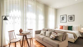 Una habitación de hotel moderna con sofá, una pequeña mesa de comedor y una cama.