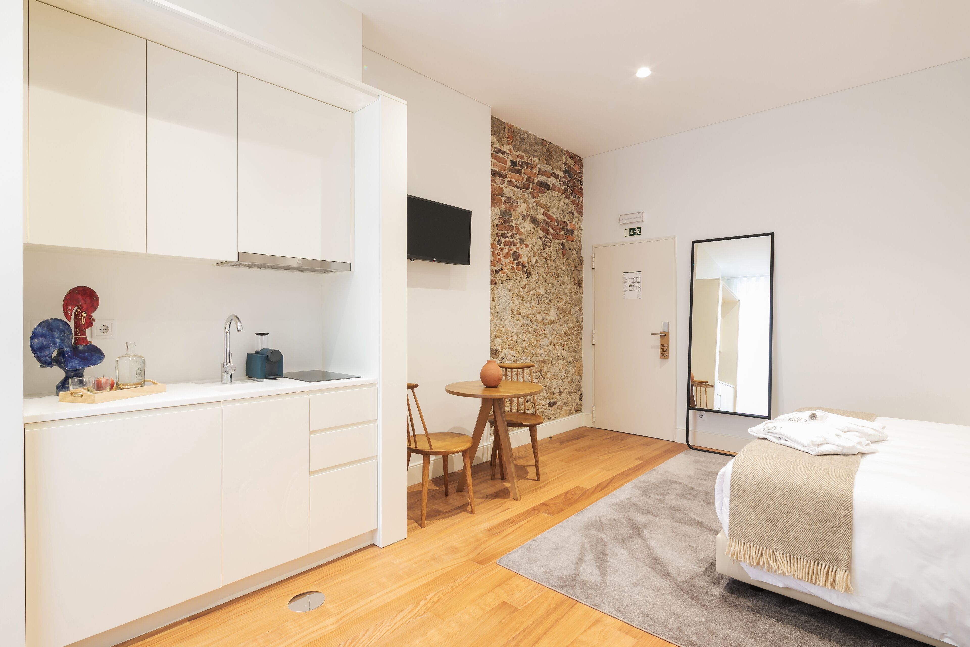 A compact hotel room with a kitchenette, a dining area, and a bed.