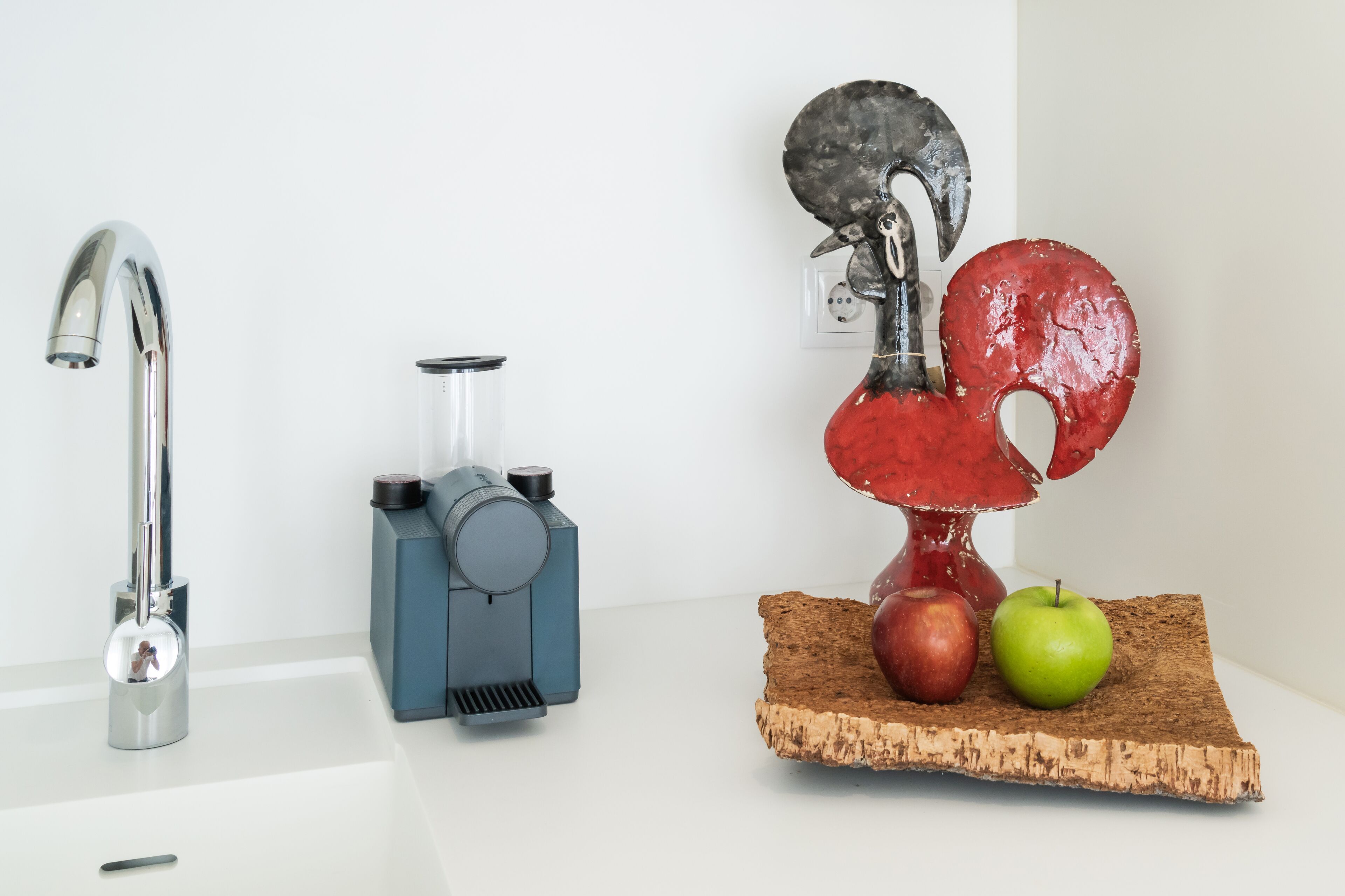 Une cuisine équipée d’un robinet moderne, d’une machine à café et d’une sculpture décorative représentant des fruits.