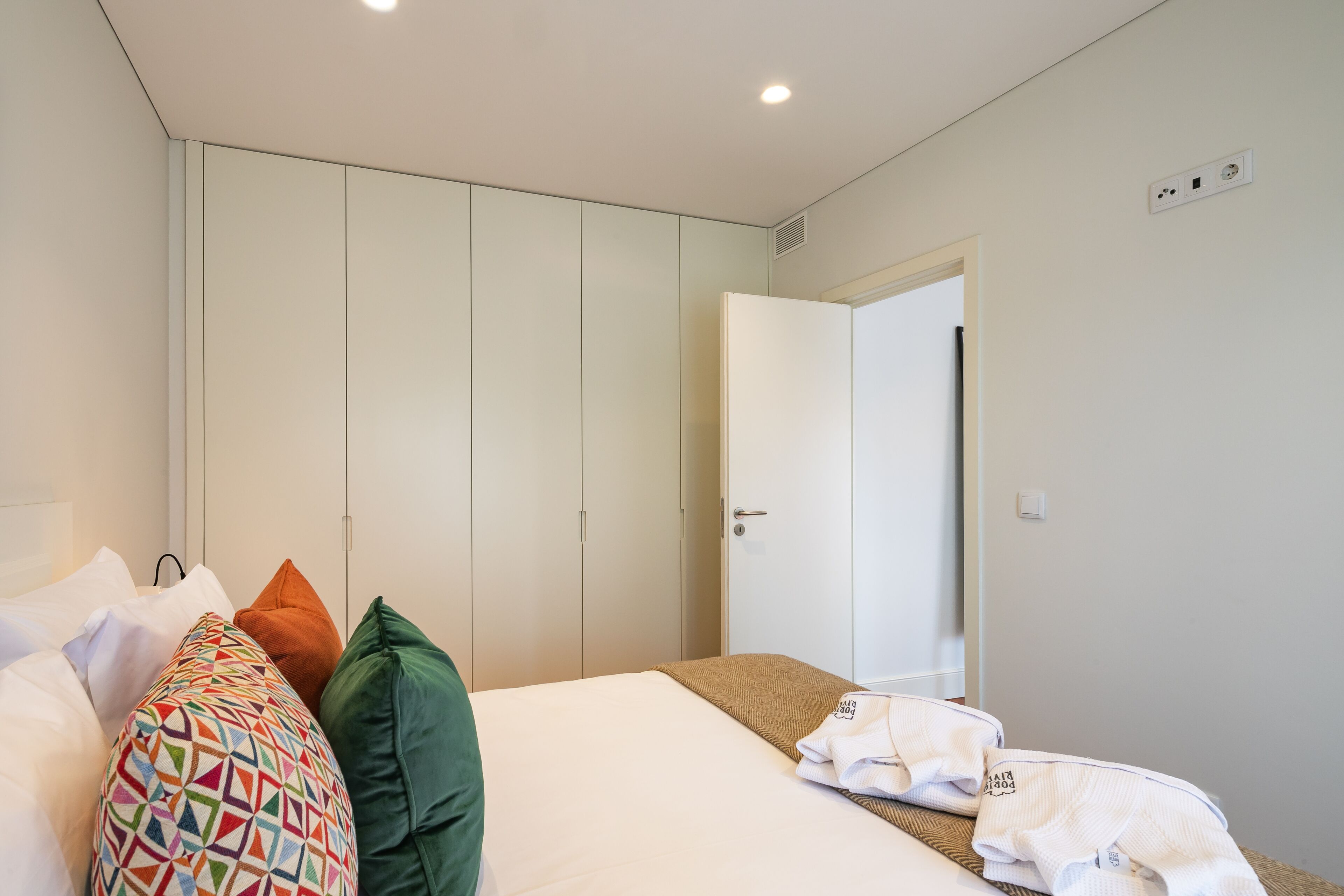 Une chambre d’hôtel avec un lit, des oreillers, une armoire et une porte.
