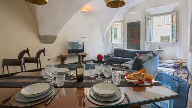 A dining area with a table set for four, a bottle of wine, and a variety of glassware.