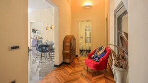 A hallway with a wooden floor, a red chair, and a potted plant.