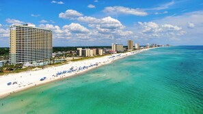 A coastal hotel with a beach view, multiple floors, and a long beachfront.
