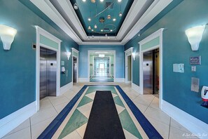 A hotel lobby with a teal color scheme, a black carpet, and a geometric patterned floor.