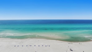 Una playa con filas de tumbonas y una vista despejada del océano.