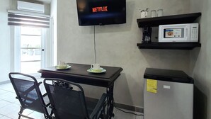 A room with a television displaying 'NETFLIX', a microwave, and a small refrigerator. - Cozumel 568 - Vacation Rental (Cozumel)