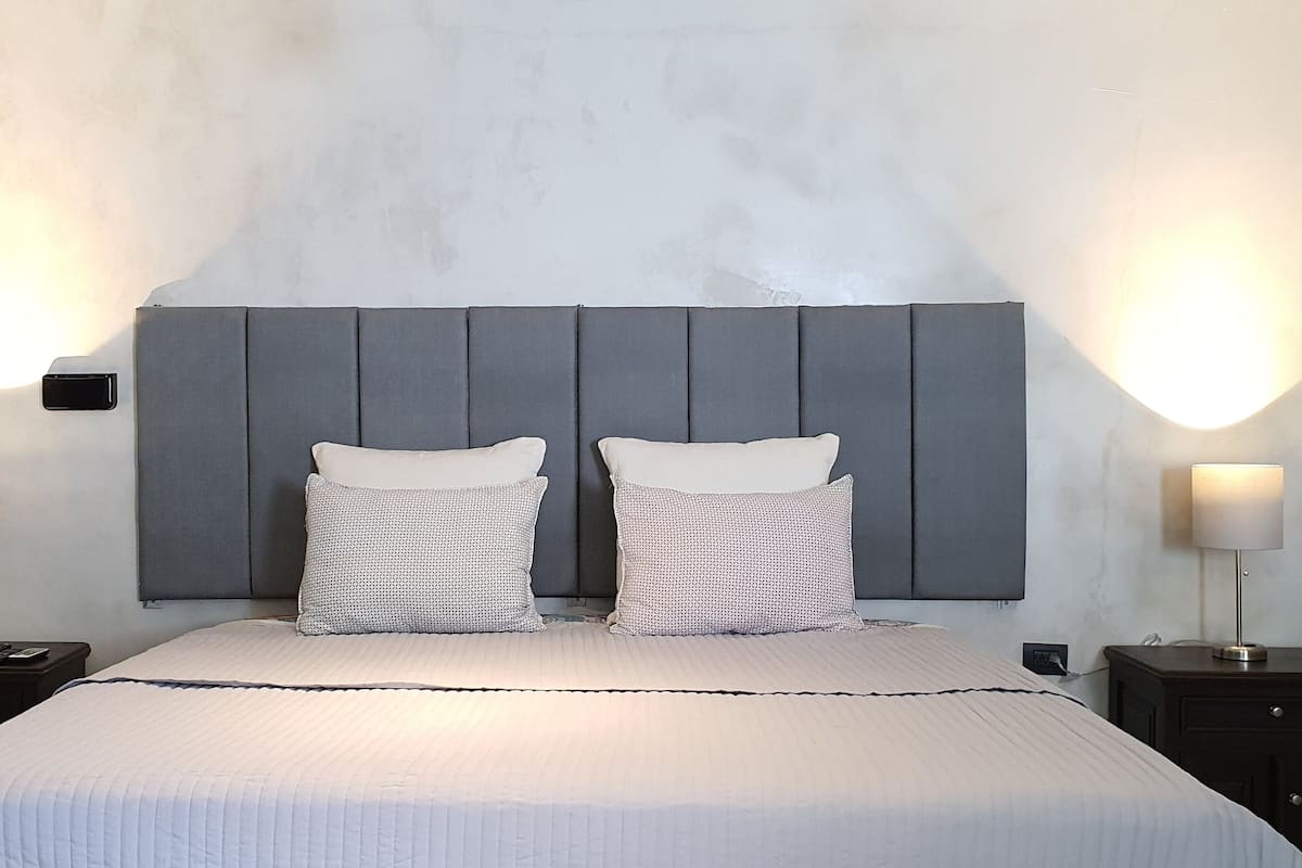 A bedroom with a large bed, two bedside tables, and wall-mounted lamps.