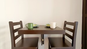 A small dining table with two chairs, a green mug, a white mug, and two plates with bowls. - Cozumel 568 - Vacation Rental (Cozumel)