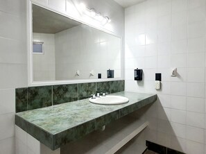Une salle de bain avec un lavabo blanc, un grand miroir et un comptoir en marbre vert.