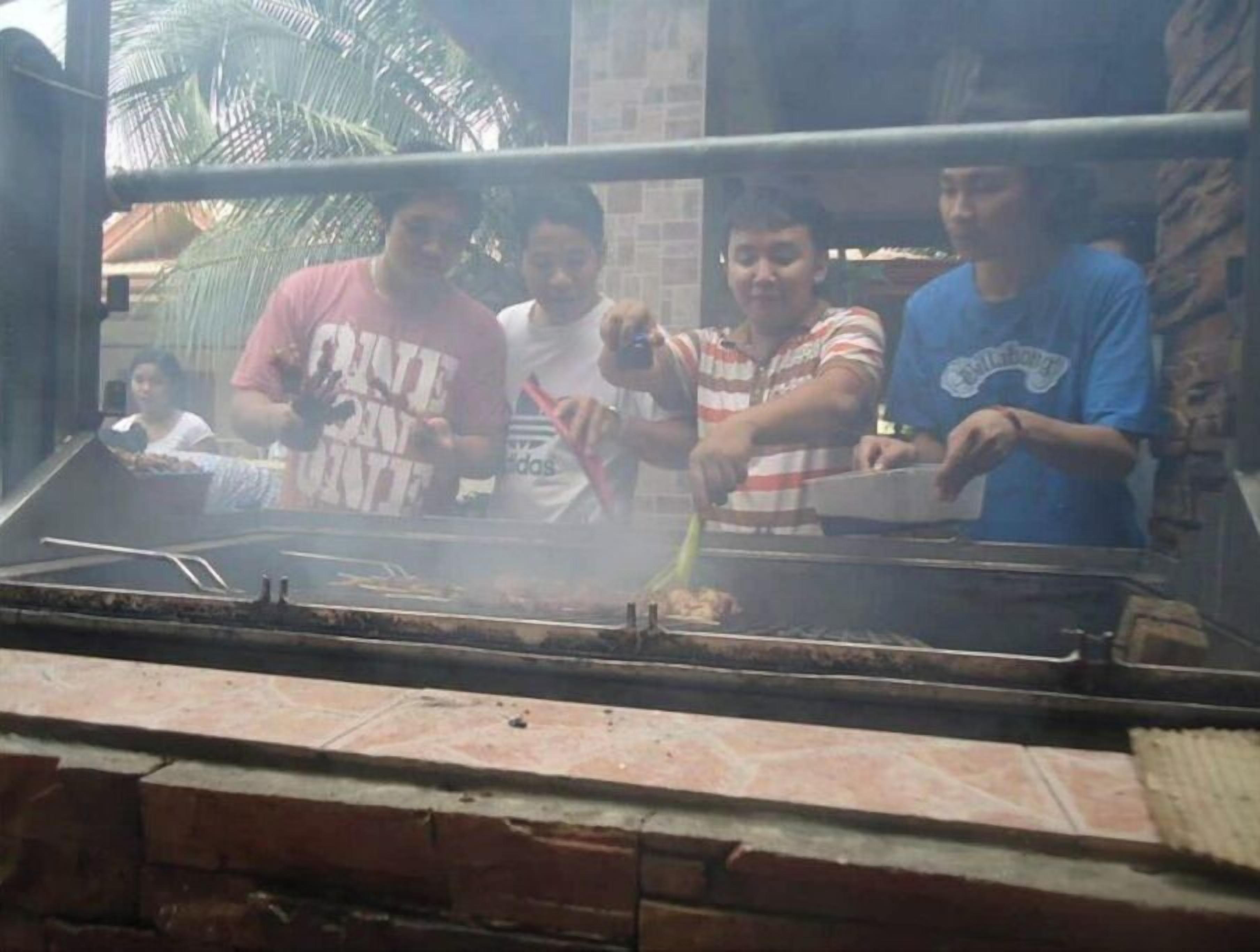 Eine Gruppe von Menschen bereitet Essen im Freien mit einem Grill zu.