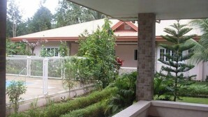 Area esterna coperta con piscina, immersa nel verde e con una casa sullo sfondo.