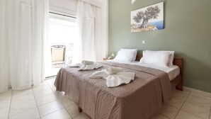A hotel room with a large bed, white linens, a painting on the wall, and a view through the window. - galini.apartments (Kassandra)