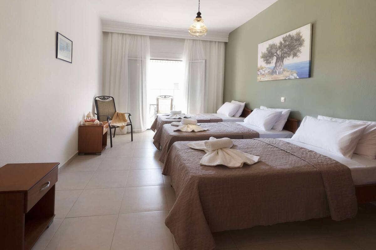 Ein Hotelzimmer mit zwei Betten, einem Schreibtisch, einem Stuhl und einem Bild an der Wand.