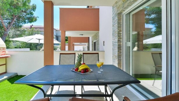 An outdoor patio with a table set for two, featuring a fruit bowl and a glass of orange juice. - Cascade villas with private garden and jacuzzi (Starigrad)